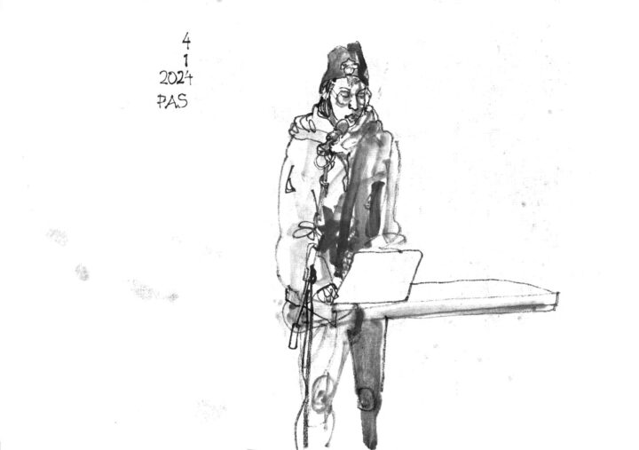 ink drawing of a musician standing at a desk with a laptop, singing into a microphone on a a microphone stand.